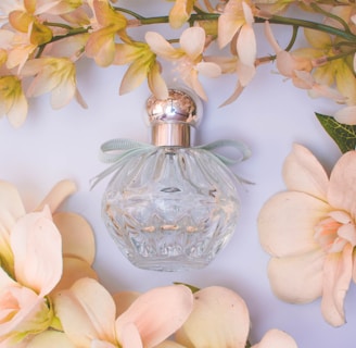 clear glass perfume bottle with white flowers