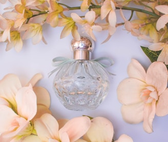 clear glass perfume bottle with white flowers