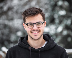 man in black hoodie wearing black framed eyeglasses