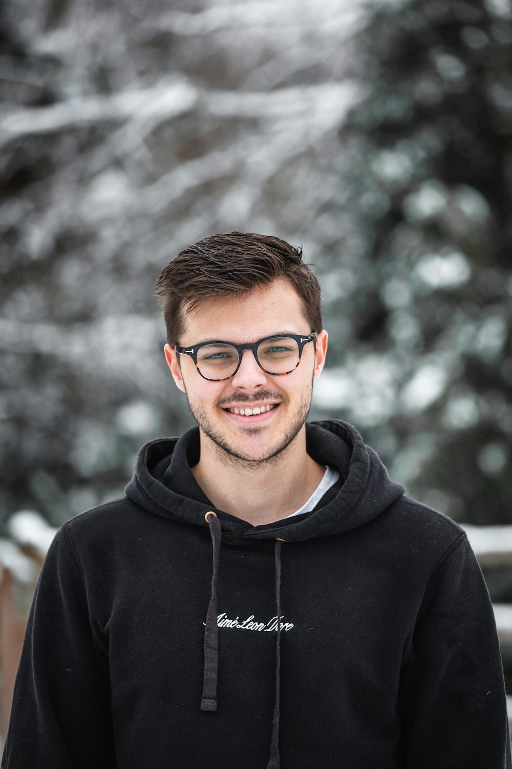 hombre con sudadera con capucha negra con gafas de montura negra