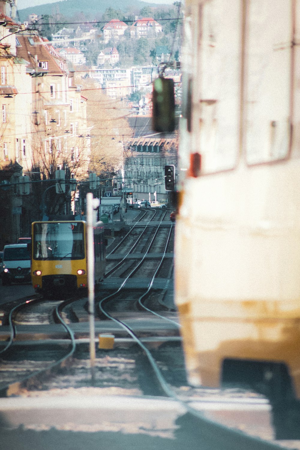 a yellow train traveling down train tracks next to tall buildings