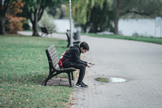 A candid moment of a young person scrolling through social media on a sunny park bench.