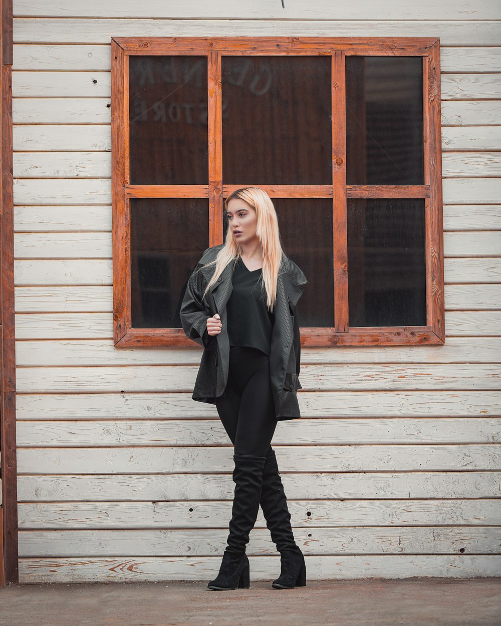 woman in black blazer standing beside brown wooden window