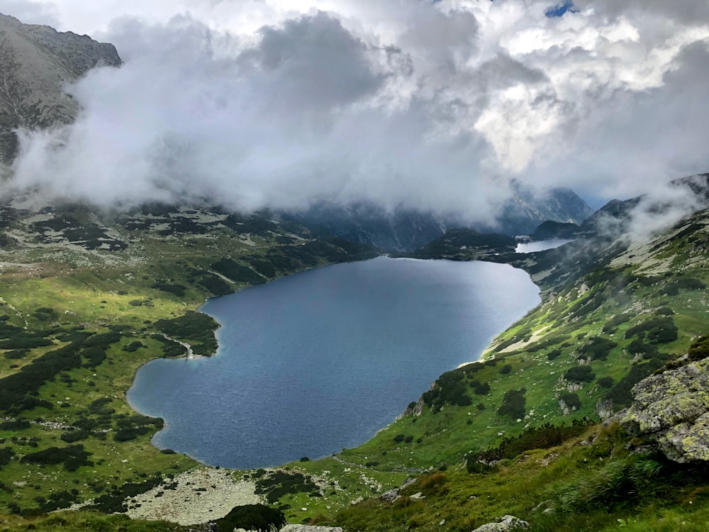 green mountains near body of water under white clouds during daytime