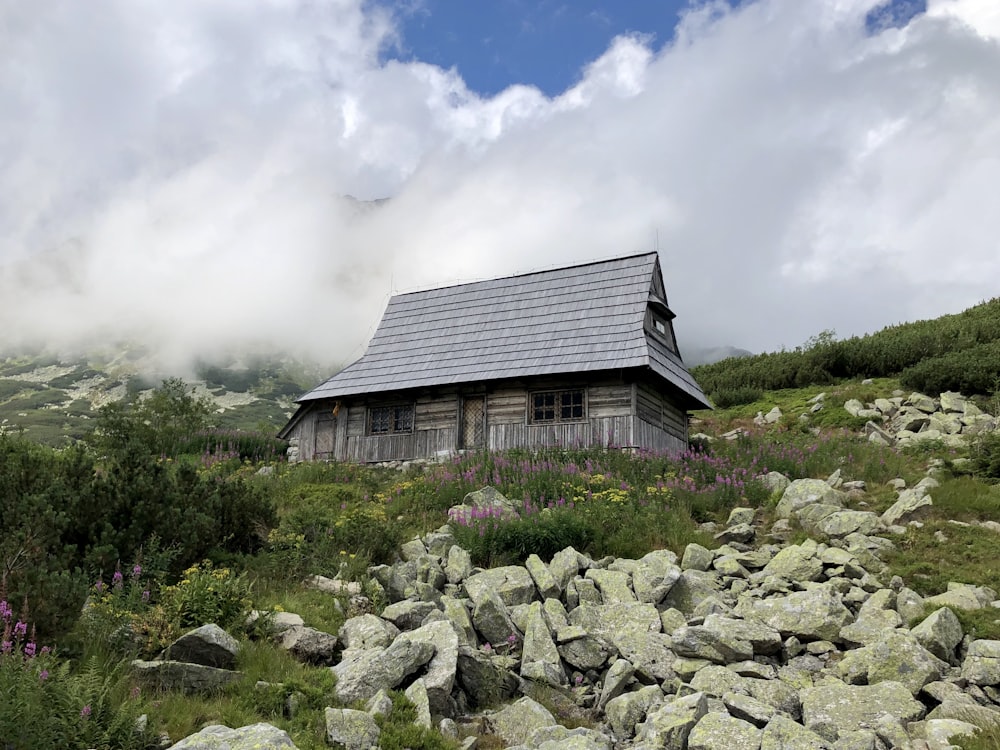 Schwarzes Holzhaus auf grünem Grasfeld unter weißen Wolken und blauem Himmel tagsüber