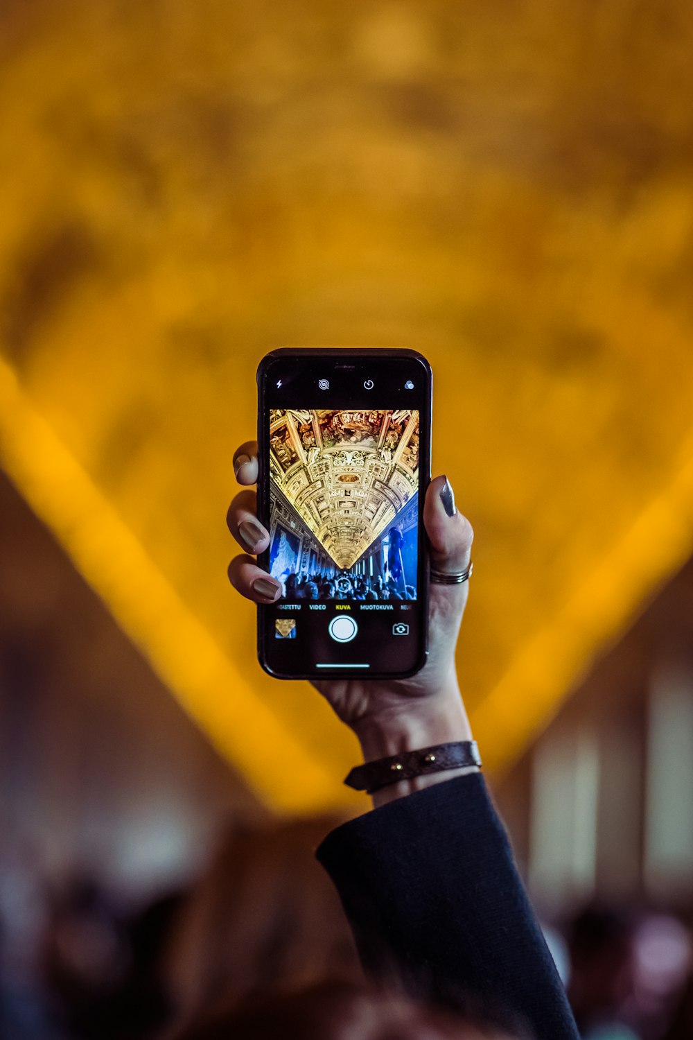 person holding iphone taking photo of yellow and white lights