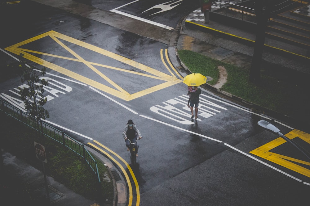 man in black jacket and yellow pants walking on pedestrian lane during daytime