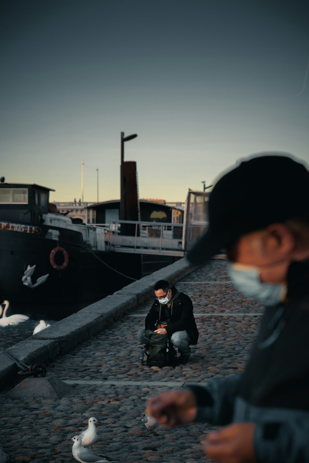 man in black jacket sitting on concrete floor during daytime