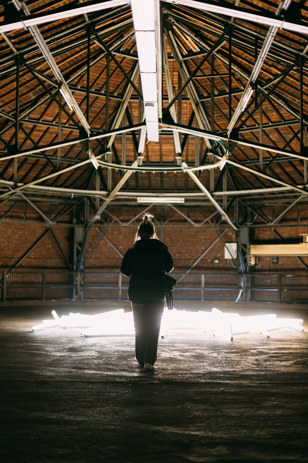 woman in black jacket and white pants standing under brown wooden ceiling