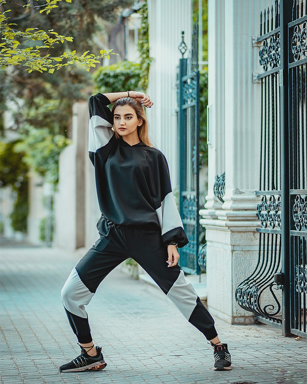 woman in black long sleeve shirt and black pants wearing black hat standing on white floor