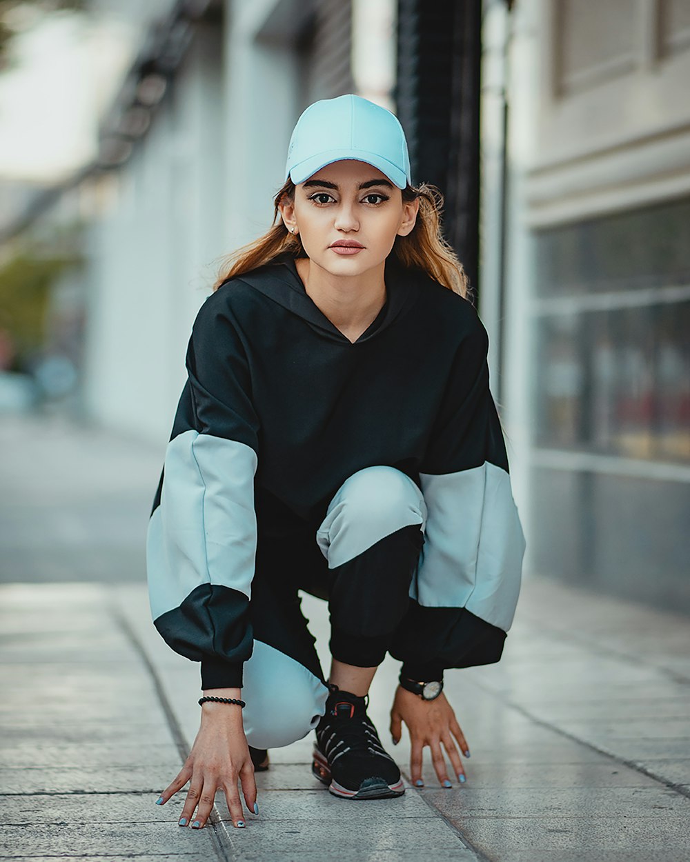 woman in black and white long sleeve shirt and black pants sitting on concrete floor