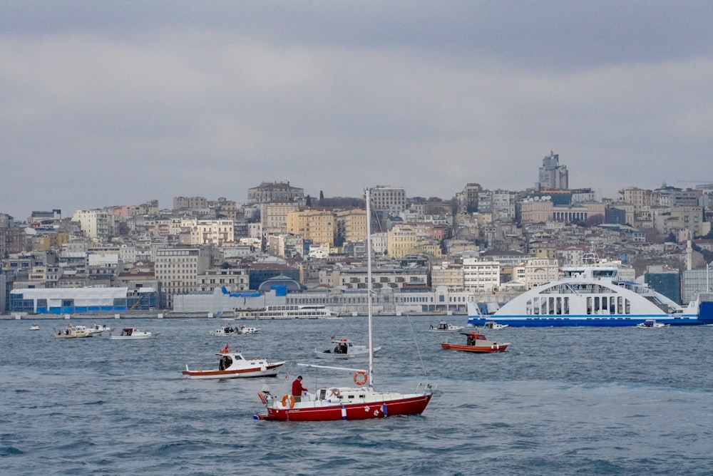 person in red kayak on body of water near city buildings during daytime