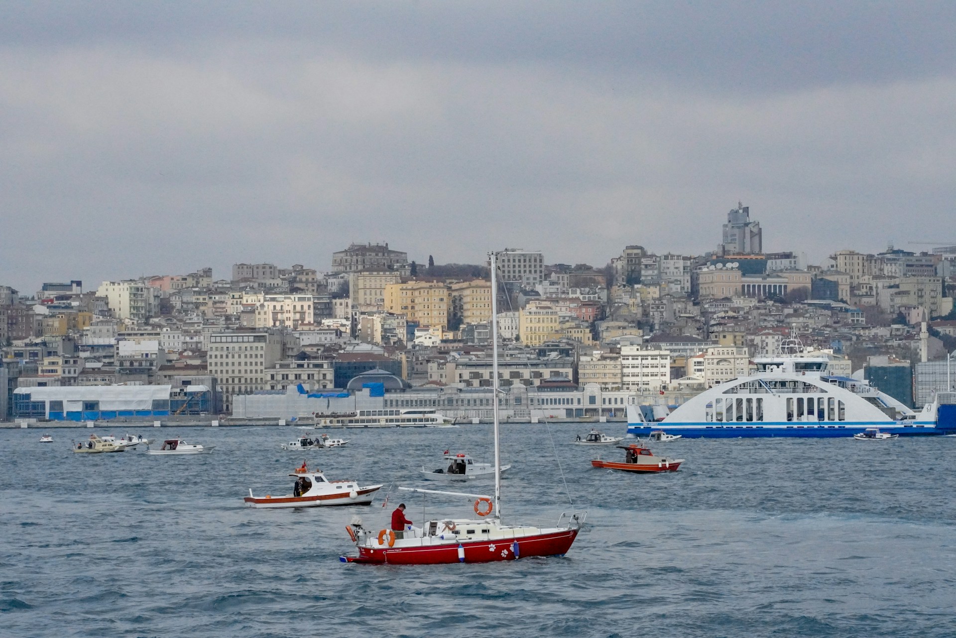 person in red kayak on body of water near city buildings during daytime