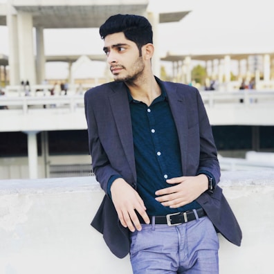 An urban backdrop featuring a man in a muted earth-tone jacket and relaxed trousers.