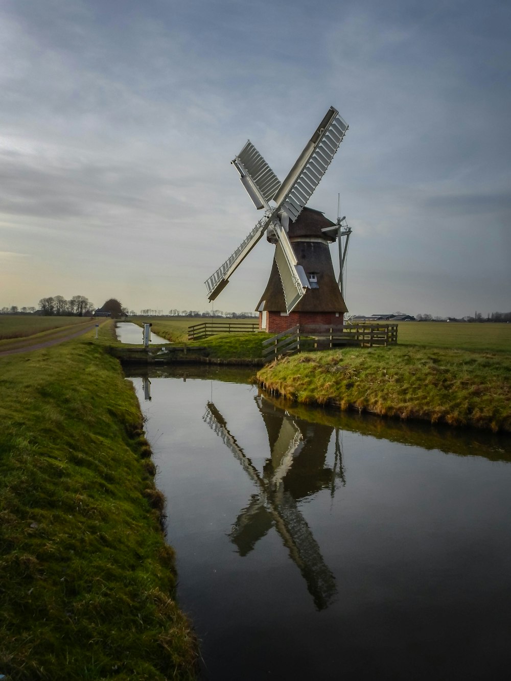 Windmühle in Flussnähe tagsüber unter bewölktem Himmel