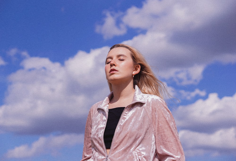 Mujer en camisa abotonada rosa bajo el cielo azul durante el día