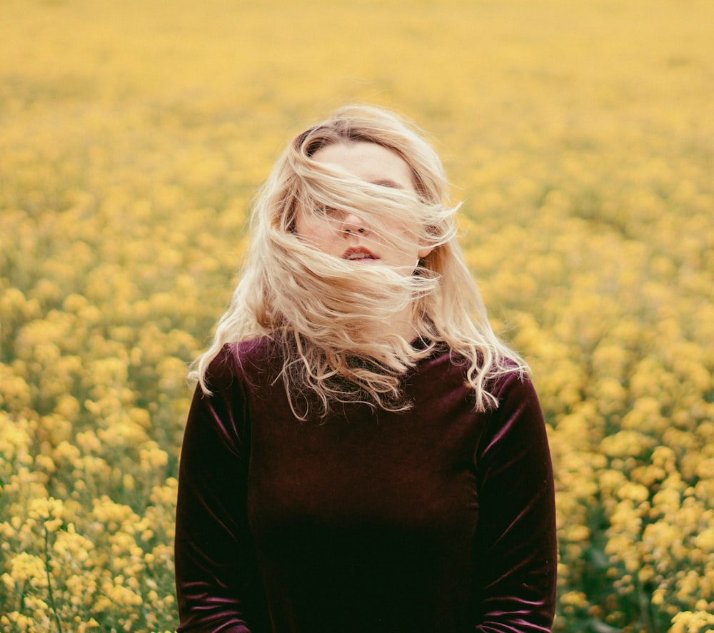 woman in black long sleeve shirt standing on yellow flower field during daytime