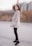 woman in gray coat and black leggings standing on gray concrete floor during daytime
