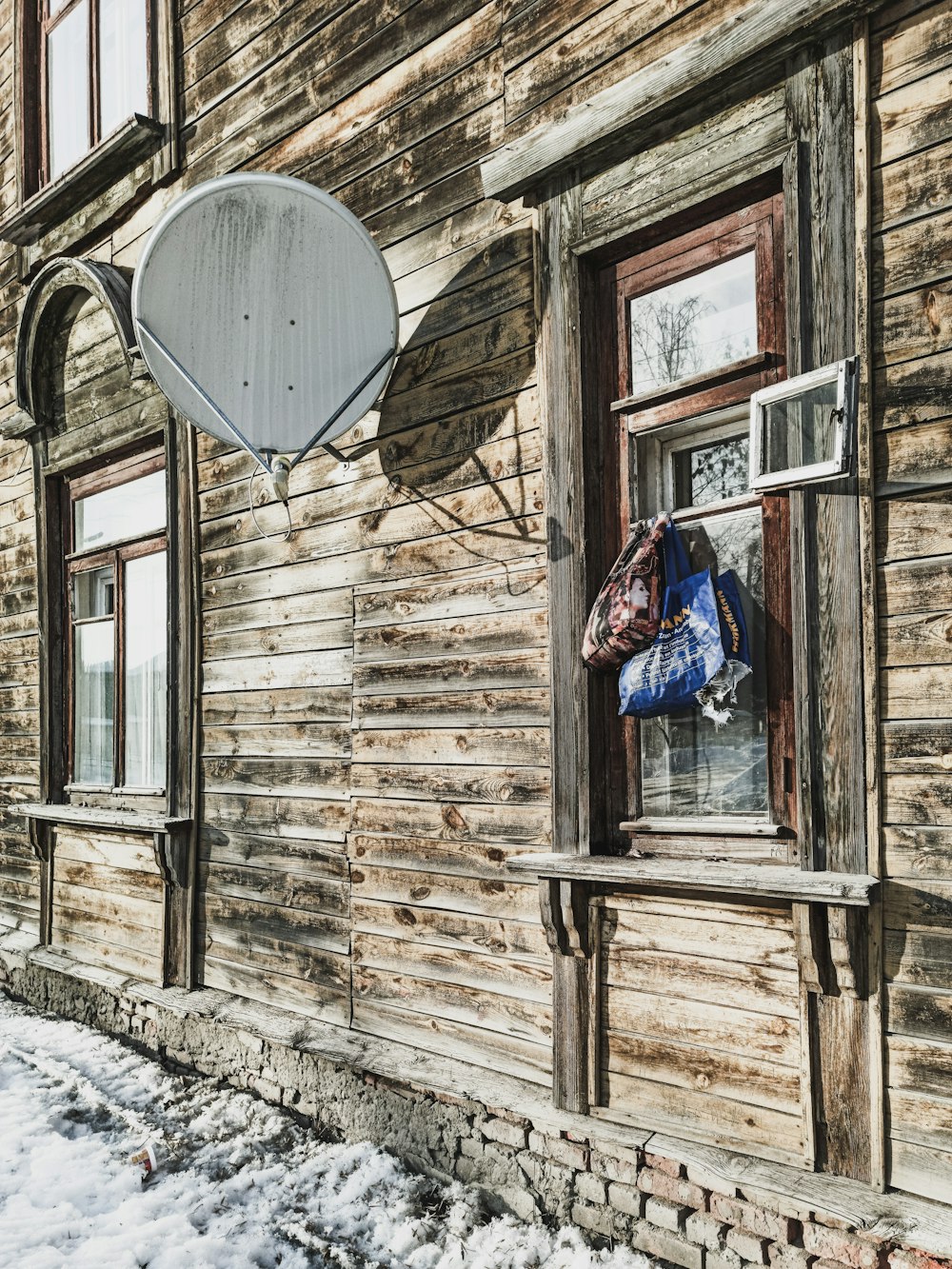 a wooden building with a satellite dish hanging from the side of it