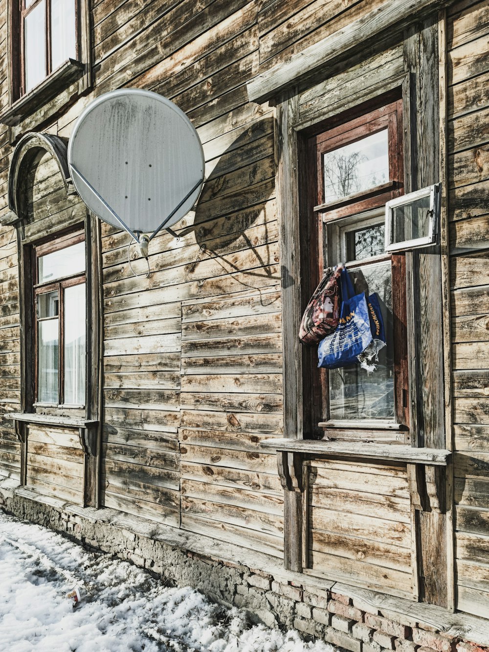 ein Holzgebäude mit einer seitlich hängenden Satellitenschüssel