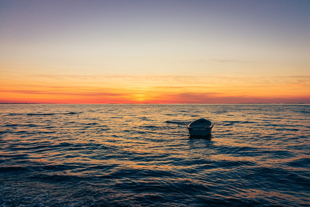 silhouette of boat on sea during sunset