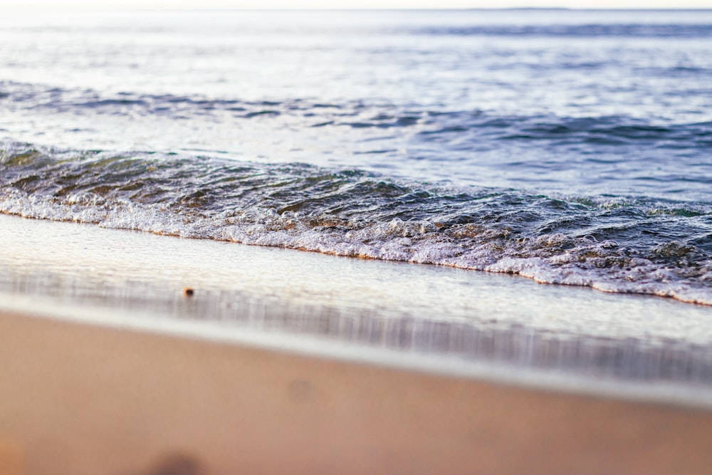 water waves on brown sand during daytime