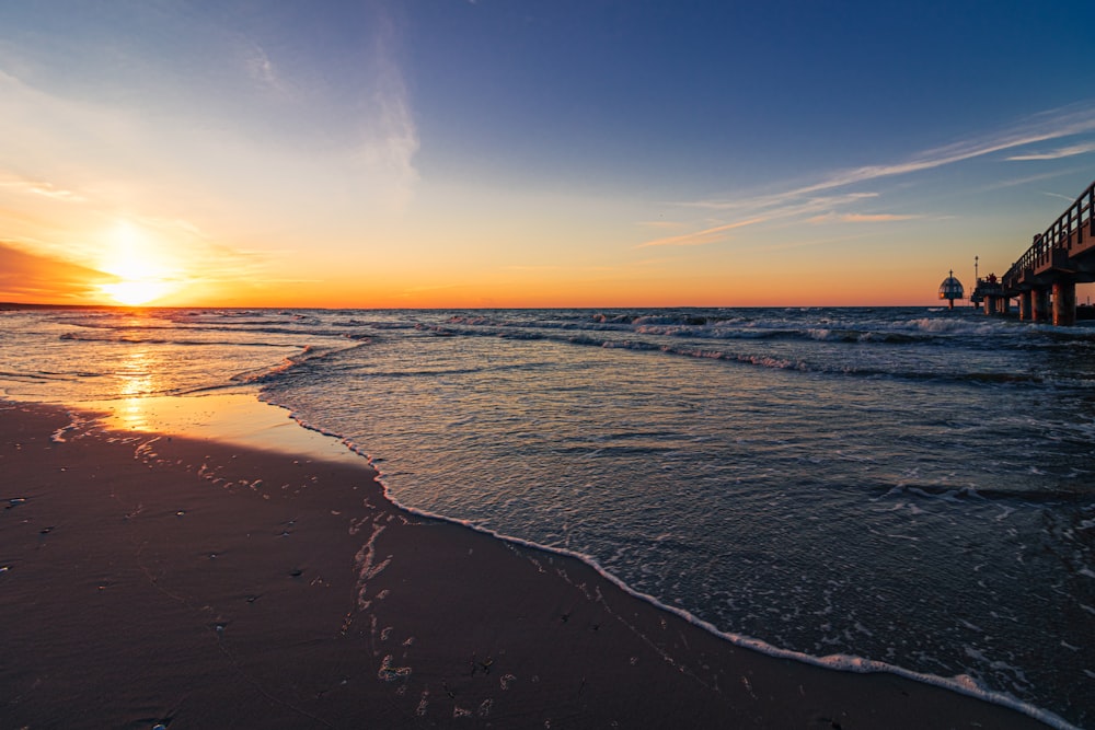 sea waves crashing on shore during sunset