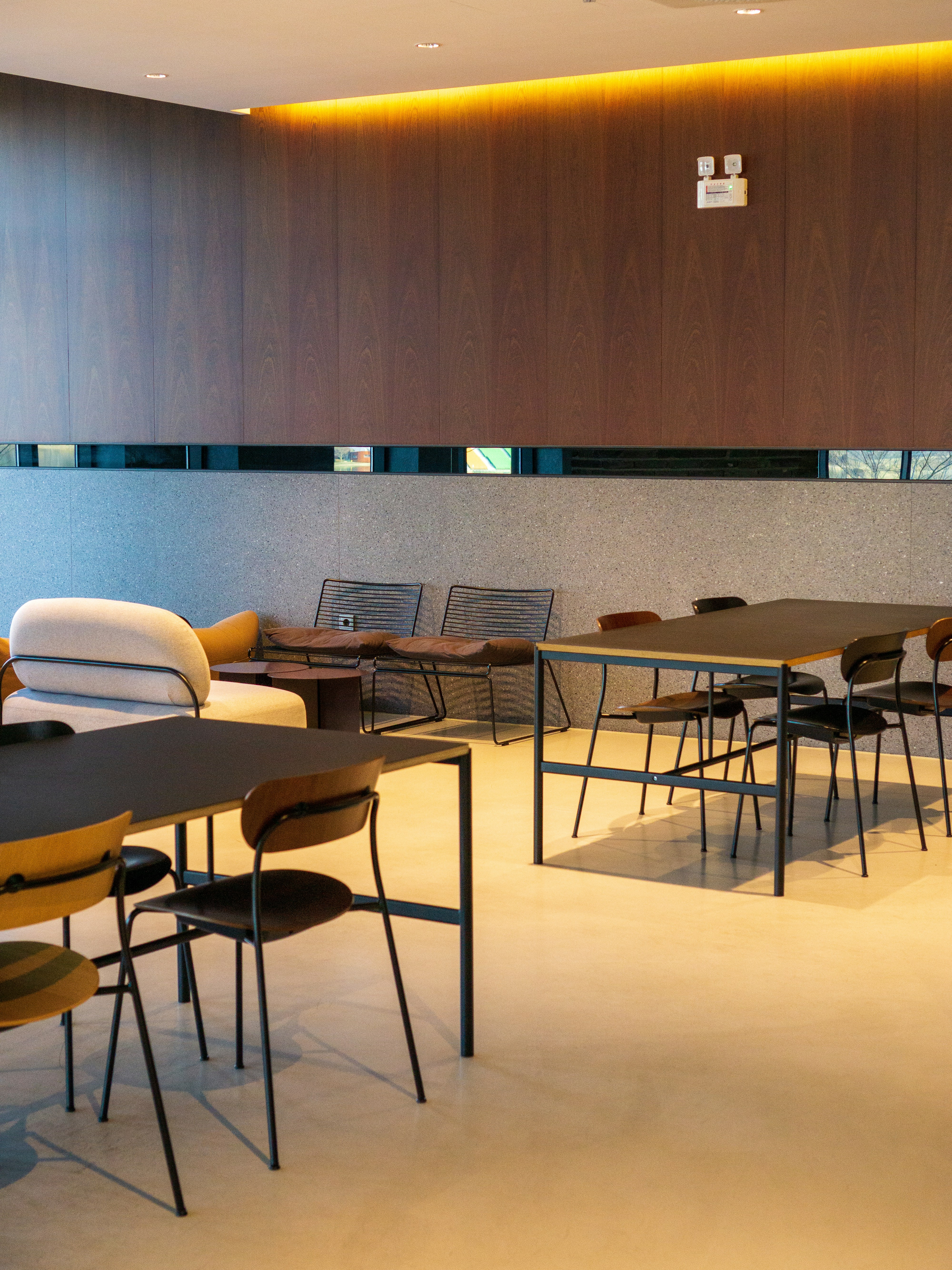 High-end hospitality lounge with dark wood panelling, warm accent lighting, deep shadow atmosphere