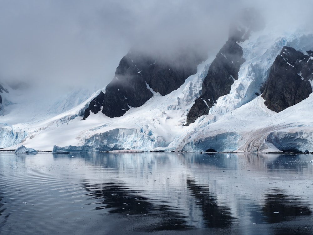 snow covered mountain near body of water during daytime