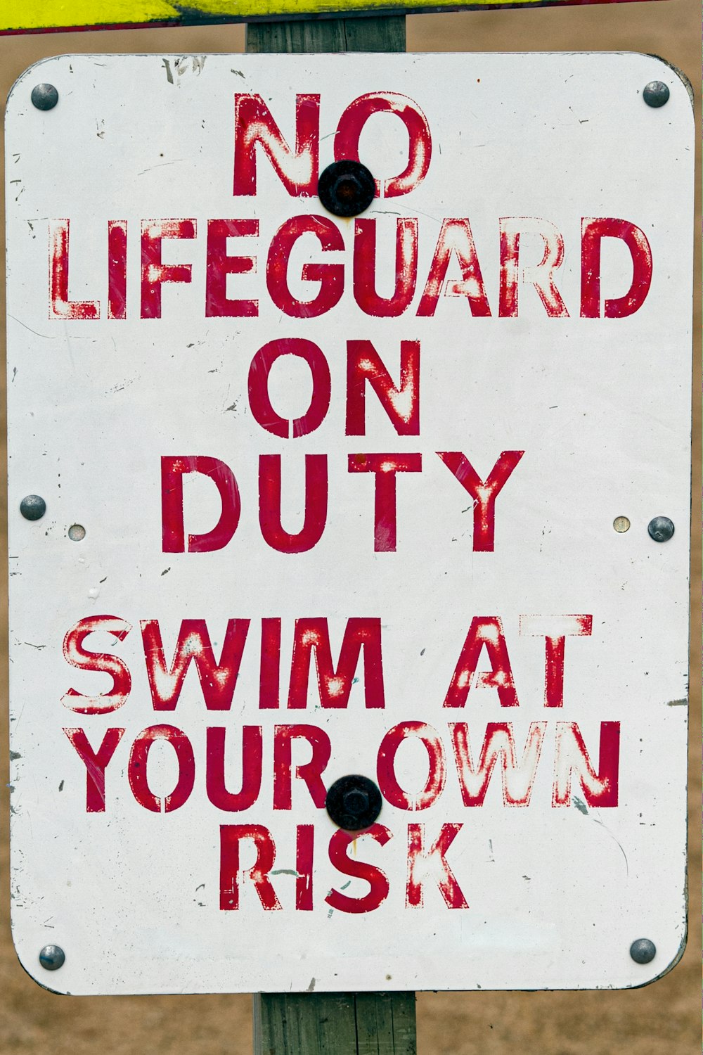 a no lifeguard on duty sign posted on a pole