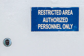 a blue sign on a white wall stating restricted area authorized personnel only