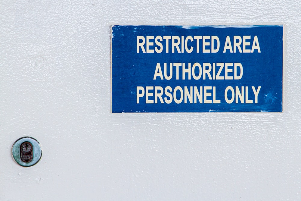 a blue sign on a white wall stating restricted area authorized personnel only
