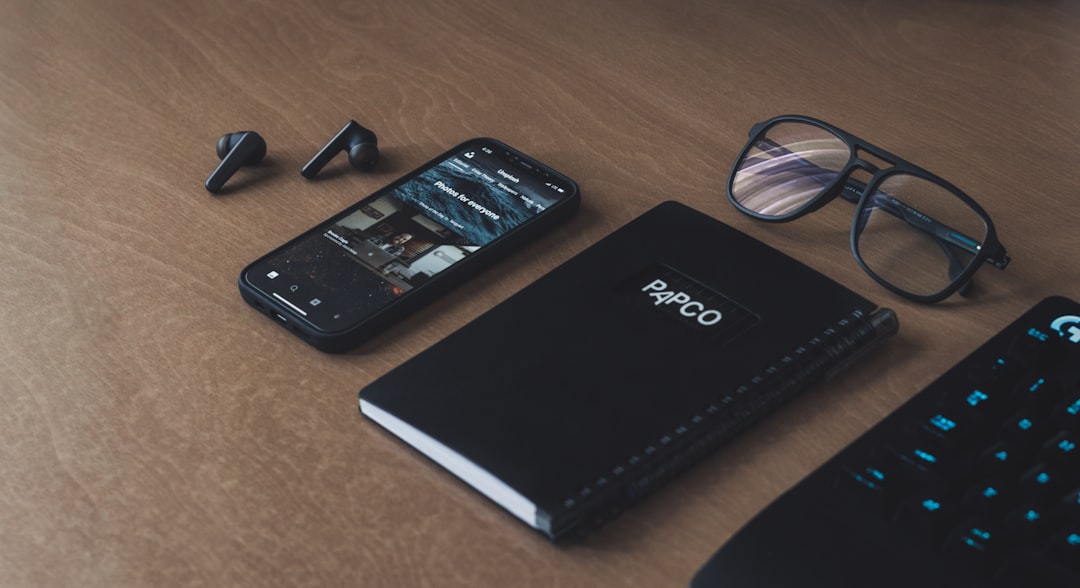 black lenovo laptop computer beside black smartphone on brown wooden table,