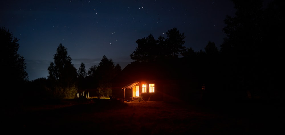 Casa de madera marrón cerca de los árboles durante la noche