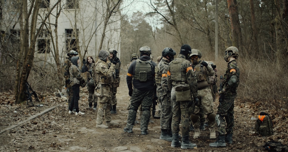 groupe de soldats en uniforme de camouflage debout sur le sol pendant la journée