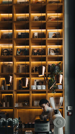 Close-up of a smiling barista serving coffee in a stylish café with ambient music speakers visible.