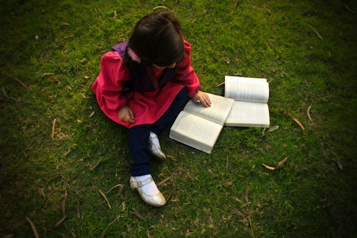 A cheerful child studying outdoors with colorful summer-themed educational materials.