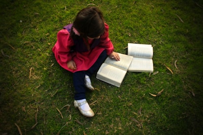 A bright, cheerful scene of a child reading a picture book under a tree.