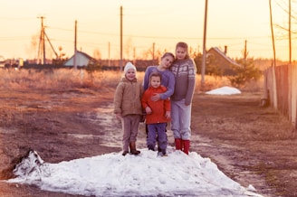 2 children standing on snow covered ground during daytime