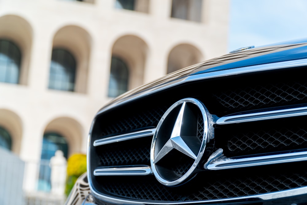 Schwarzes Mercedes-Benz-Auto tagsüber vor beigefarbenem Betongebäude