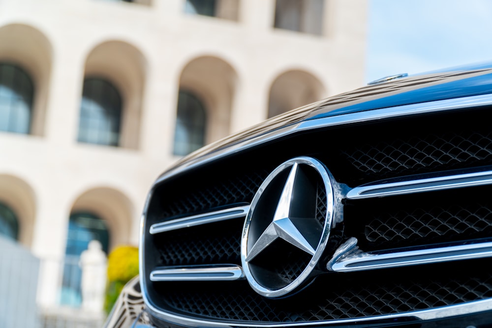 Coche Mercedes Benz negro frente a un edificio de hormigón beige durante el día