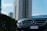 Luxury car parked on a modern city street with skyscrapers in the background.