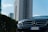Luxury car parked on a modern city street with skyscrapers in the background.