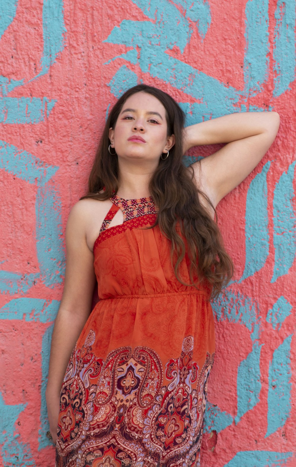 woman in red sleeveless dress standing beside red wall