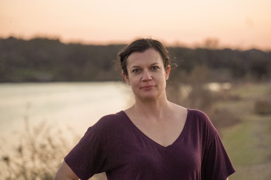 woman in purple scoop neck shirt standing on field during daytime