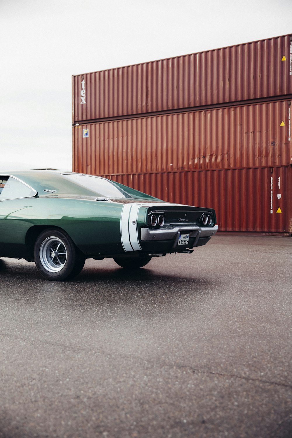 Chevrolet Camaro verde acqua parcheggiata vicino al muro di metallo rosso