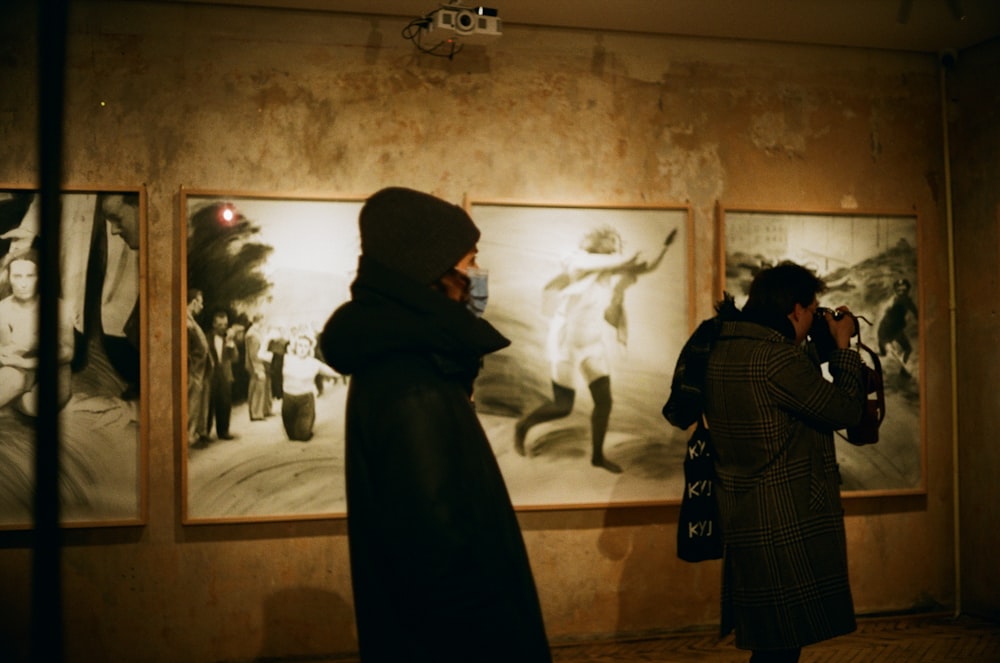 hombre con abrigo negro de pie frente a la pintura