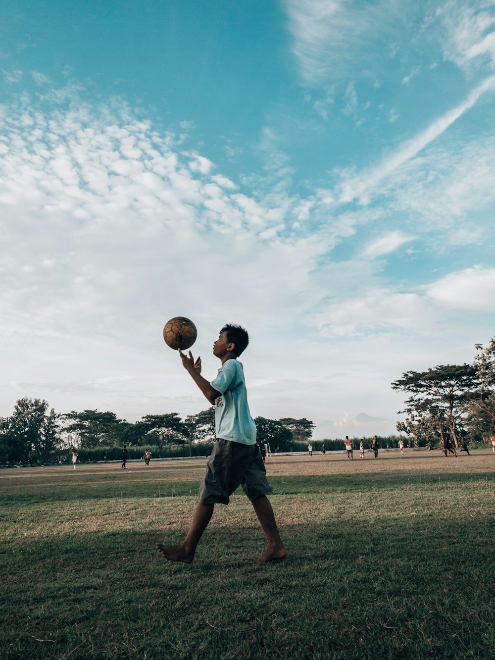 man in blue shirt and black shorts playing basketball on green grass field during daytime