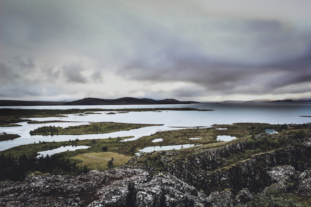 green grass field near body of water under cloudy sky during daytime