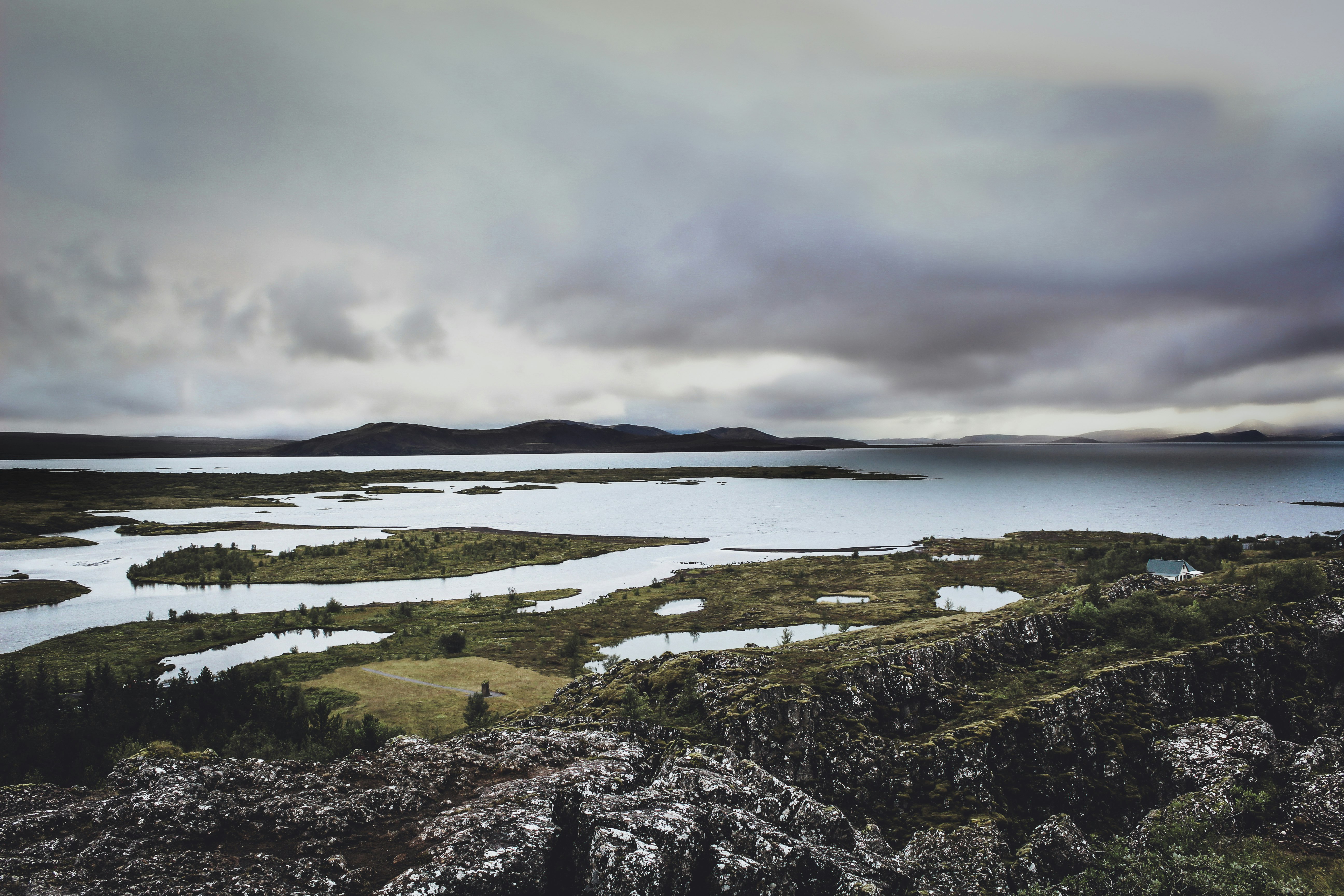 green grass field near body of water under cloudy sky during daytime